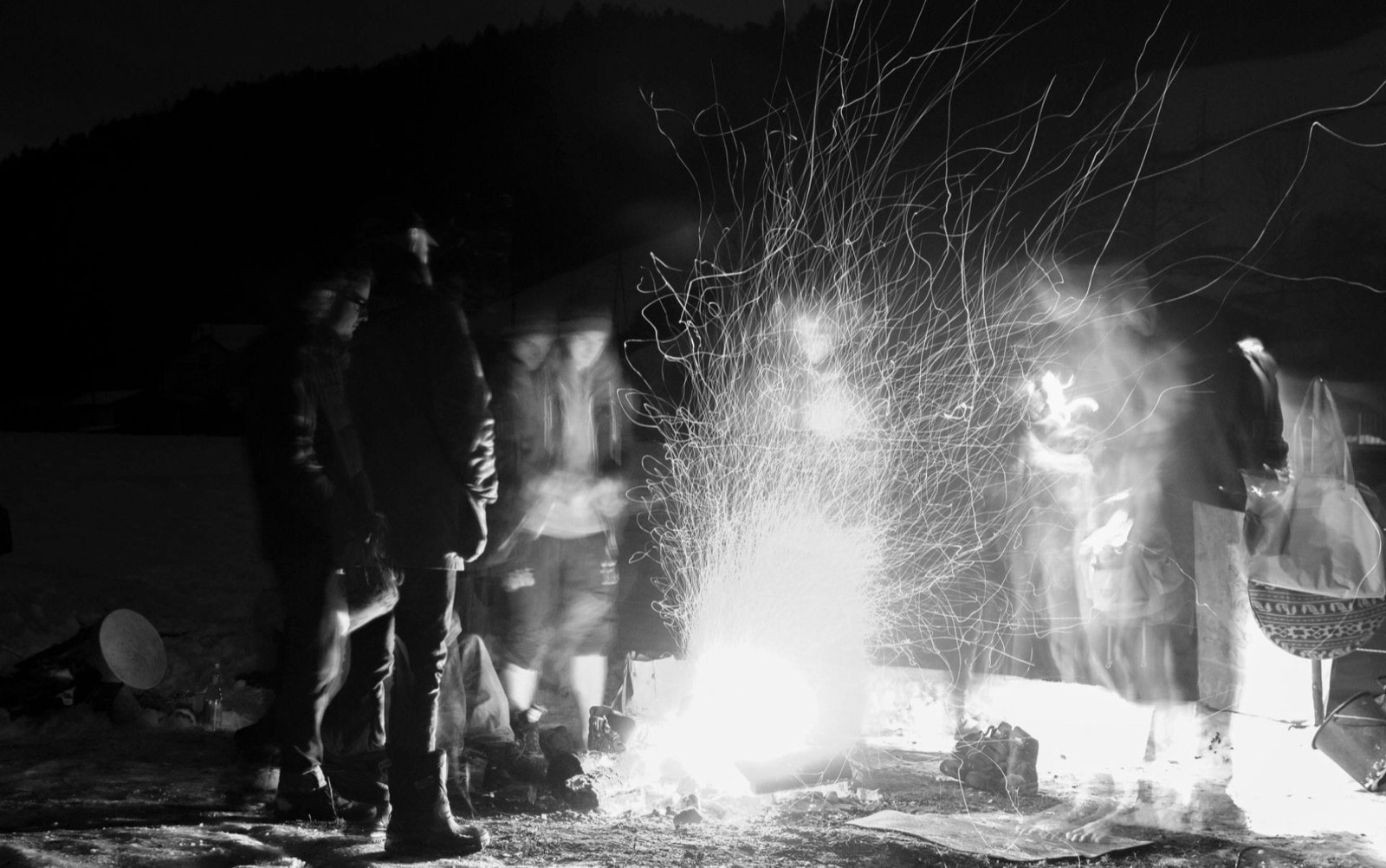 Lichtmalerei aus Feuerfunken bei Nacht, Silhouetten von Männern im Kreis